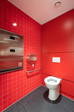 Red tiled wall washroom with brushed satin stainless steel fittings